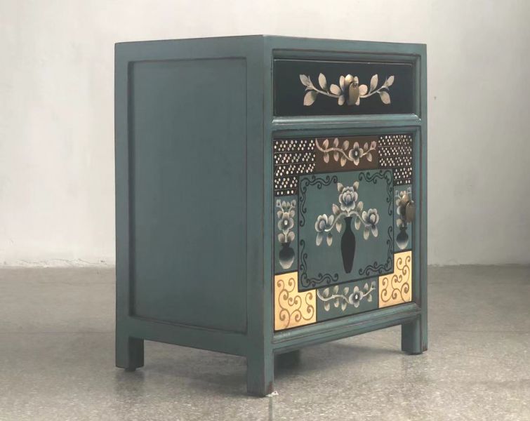 Petrolfarbener Nachttisch mit floralen und grafischen Elementen auf der Vorderseite, Schublade mit goldenen Blättern und Tür mit ornamentalem Blumenmuster.