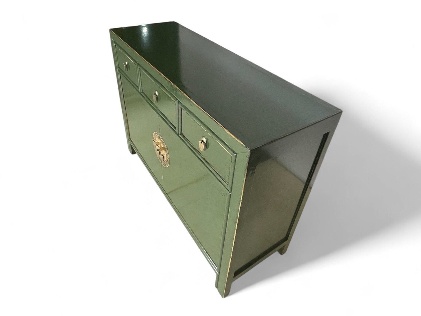 Grüne Vintage-Kommode mit glänzender Oberfläche, schräg von oben fotografiert, betont elegante Linienführung und Lackierung.