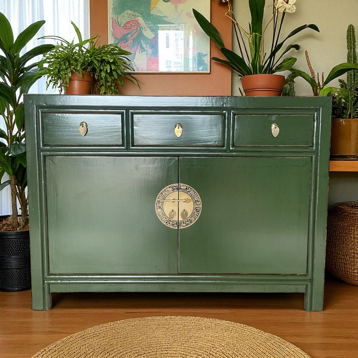 Grüne Kommode im stilvollen Wohnzimmer, dekoriert mit Pflanzen, Kunstbild an der Wand und hellem Tageslicht.